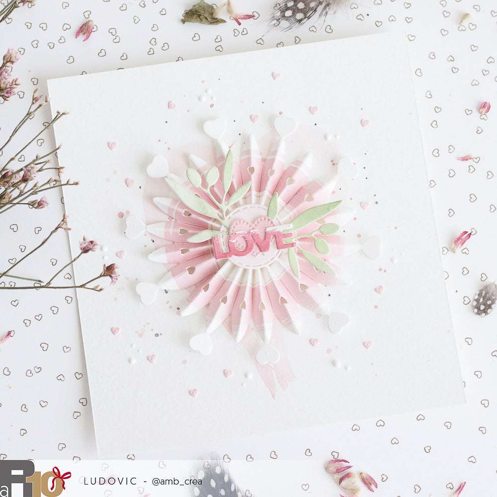 Handgefertigte Karte mit rosafarbenem "LOVE", Papierherzen, Blättern und Herzmustern - gestaltet mit dem Designpapier von Alexandra Renke und dem Stanzset "Rosette mit Herzen" für ein charmantes Finish.