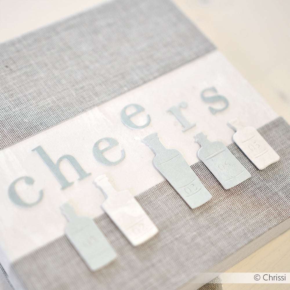 Eine strukturierte Karte von Alexandra Renke mit fünf pastellfarbenen Flaschenausschnitten auf grauem und weißem Hintergrund, hergestellt mit DieCut Systemen und hochwertigem Designpapier.