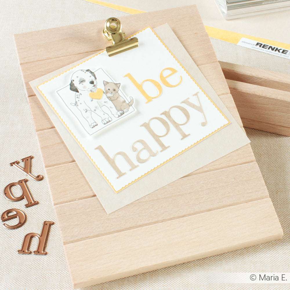Ein hölzernes Klemmbrett von Alexandra Renke enthält eine Karte mit der Aufschrift "be happy", verziert mit Hunde- und Katzenillustrationen, hergestellt mit Designpapieren und akzentuiert mit Motivstanze Serifbuchstaben.