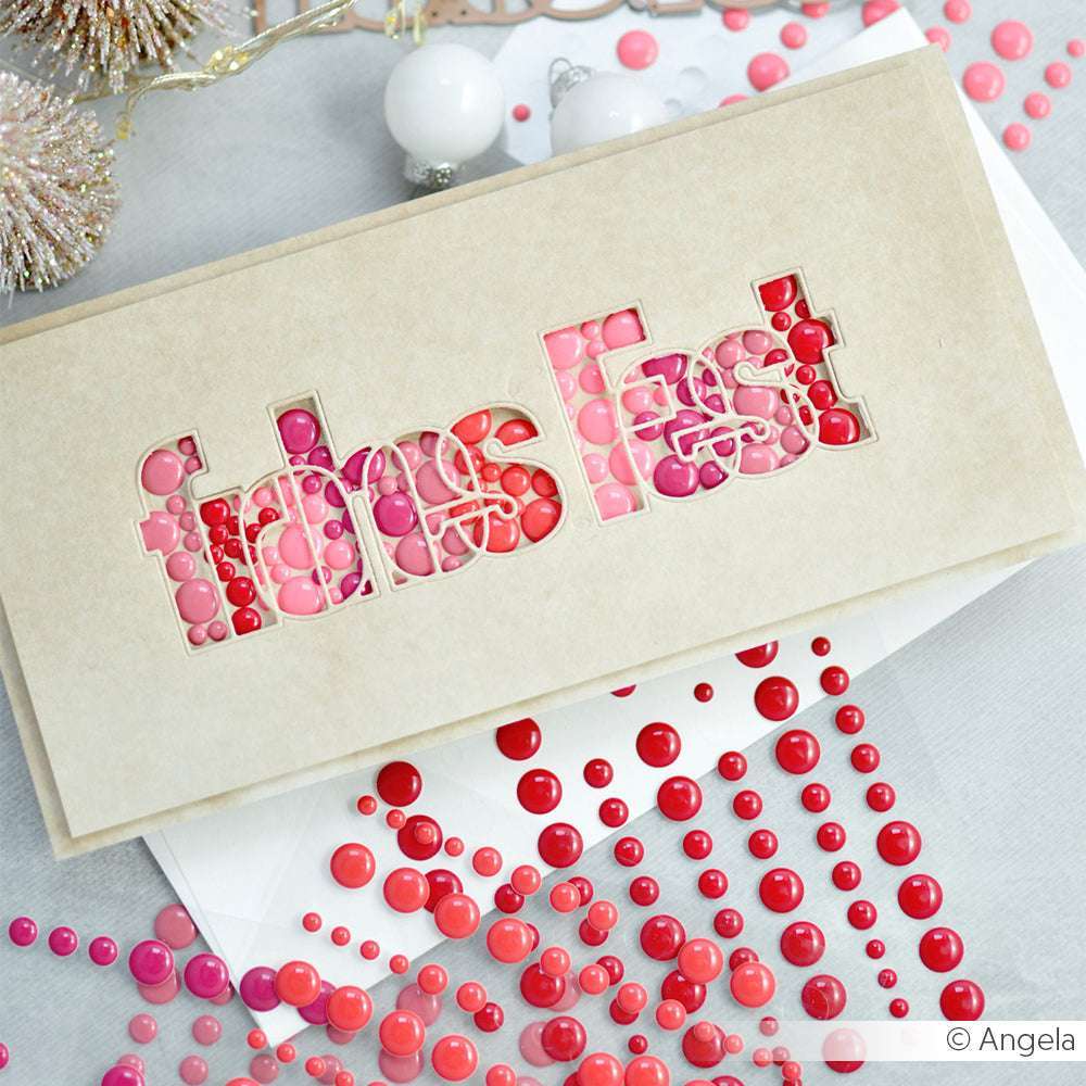 Die beigefarbene Karte von Alexandra Renke ist mit einem ausgeschnittenen Text von DieCut Systeme versehen, der mit roten und rosafarbenen Punkten gefüllt und mit passenden Zierperlen akzentuiert ist.