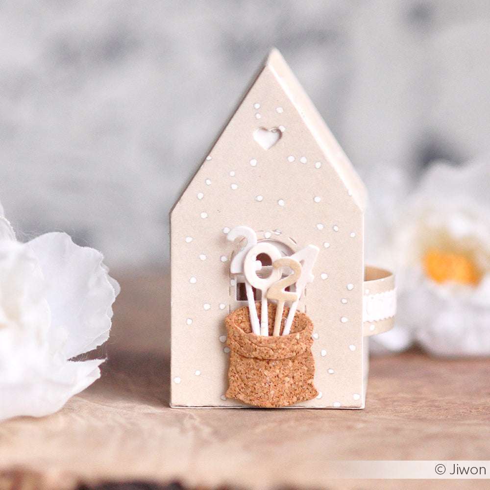 Eine kleine Hausdekoration von Alexandra Renke mit Motivstanze Zahlen am Stiel für 2021 Sticks in einem Korkbeutel, umgeben von weißen Blumen.