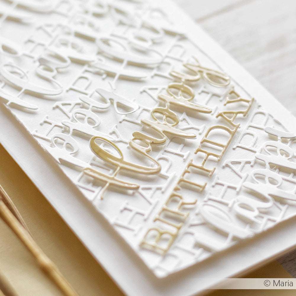 Nahaufnahme einer weiß-gold geprägten Happy-Birthday-Karte von Alexandra Renke mit einem stilvollen Schriften-Duo-Textdesign, das mit der Motivstanze Happy Birthday Stanzsysteme für einen Layering-Effekt hergestellt wurde.