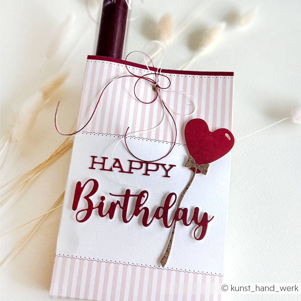 Alexandra Renke Geburtstagskarte mit Schriften-Duo Happy Birthday Text und rotem Herzluftballon, gestaltet mit der Motivstanze Happy Birthday auf stilvoll gestreiftem Hintergrund.
