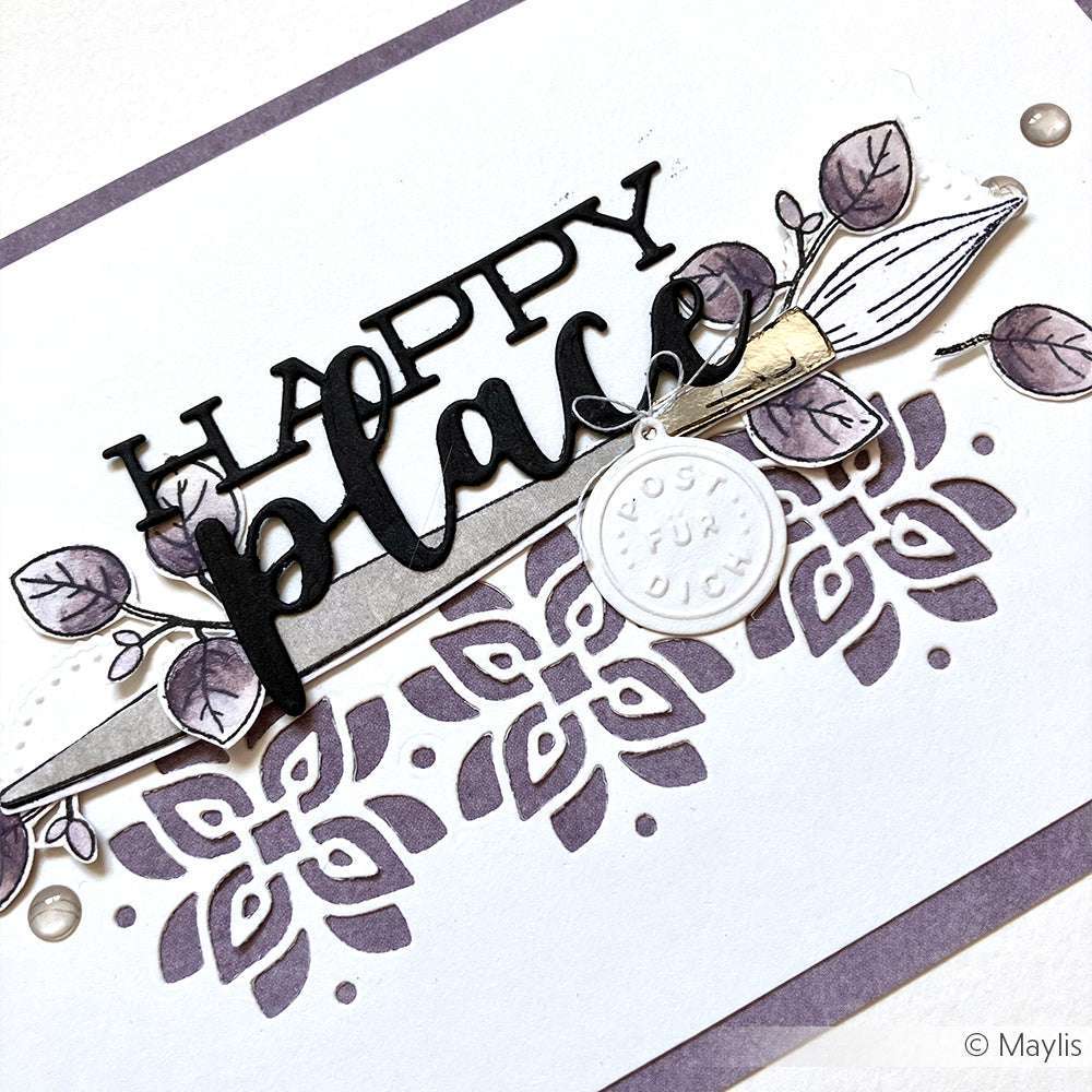 Handgefertigte Karte von Alexandra Renke mit dem Text "Happy place", Blumen- und Blattmotiven mit Designpapieren und Motivstanze Schriften-Duo Die, verziert mit einem runden weißen Anhänger auf lavendelfarbenem Hintergrund.