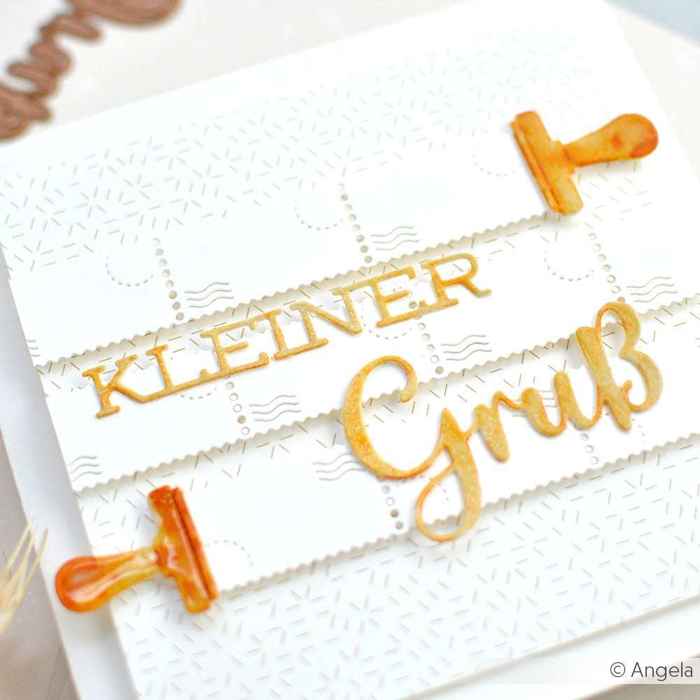 Weiße Karte mit Kleiner Gruß in Gold (Motivstanze Schriften-Duo Kleiner Gruß von Alexandra Renke) und zwei orangefarbenen Schnullern auf strukturiertem Designpapier.