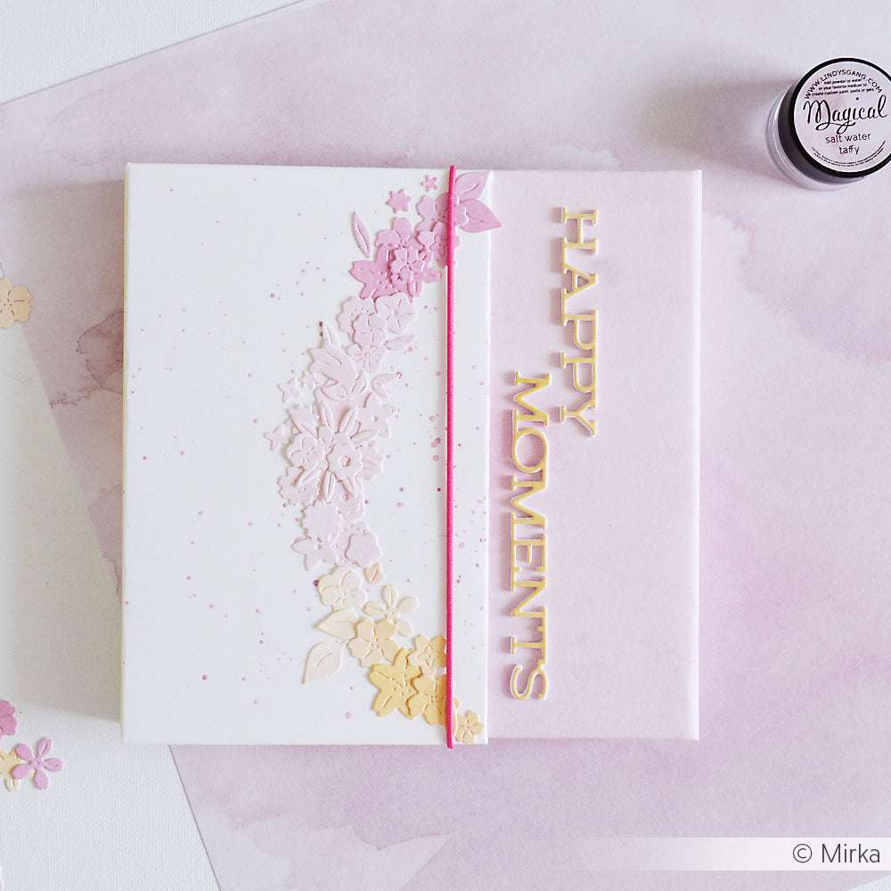 Eine pastellfarbene Karte von Alexandra Renke, die mit Designpapieren und Blumenmustern gestaltet wurde, zeigt HAPPY MOMENTS in goldenen Buchstaben auf einem rosa Aquarellhintergrund.