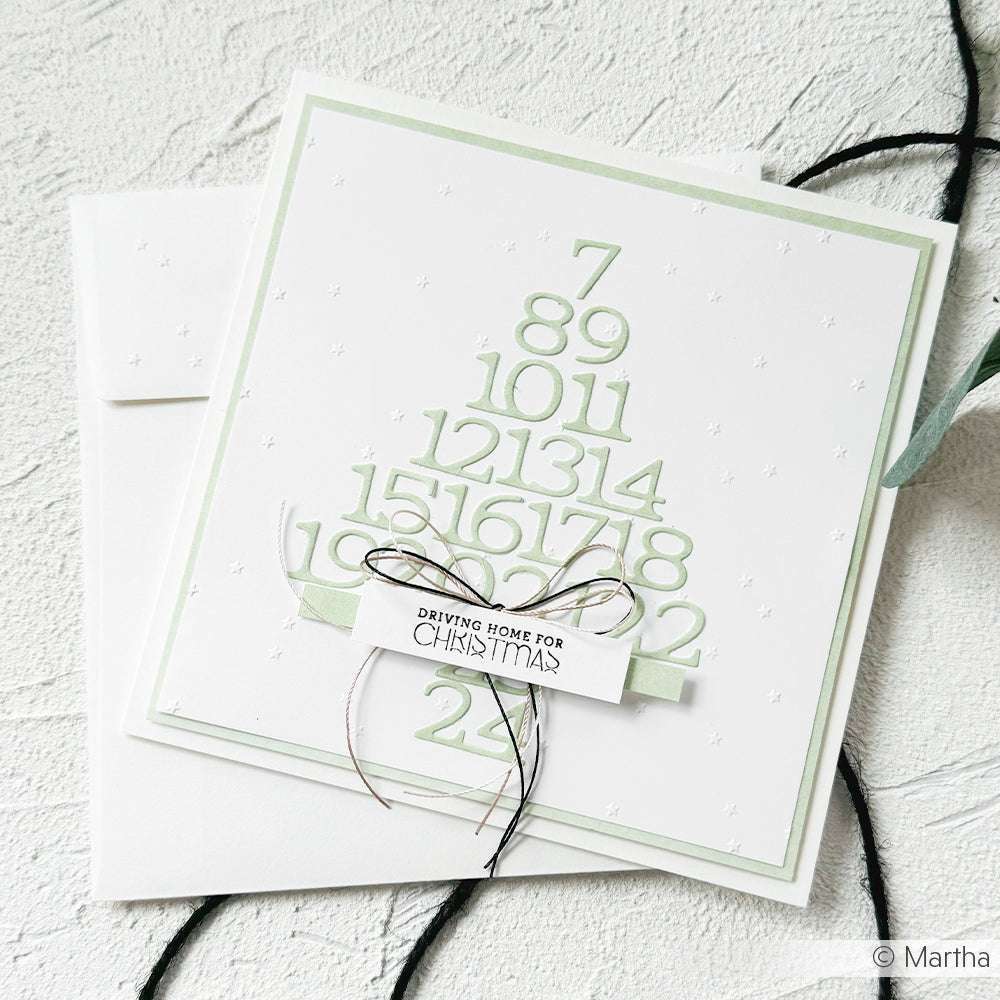 Weiße Weihnachtskarte, gestaltet mit Alexandra Renke Designpapieren, mit Zahlen, die mit der Stanze Kleine Serifenzahlen in Form eines Baumes gestanzt wurden, und einem mit Schnur gebundenen Anhänger "Driving Home for Christmas".