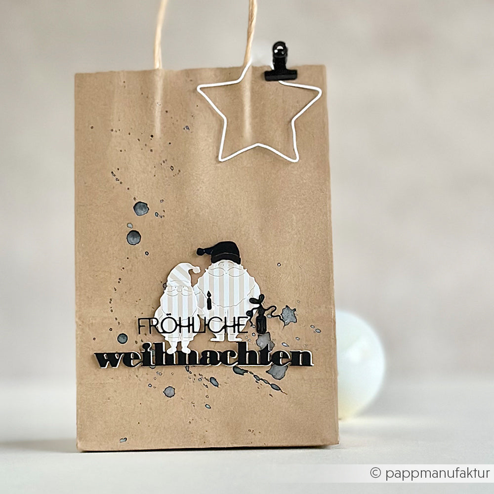 Alexandra Renke Geschenktüte aus braunem Papier mit zwei Wichteln, ausgeschnittenem Text "Fröhliche Weihnachten" mit einer Weihnachtsmotivstanze und einem Sternclip.