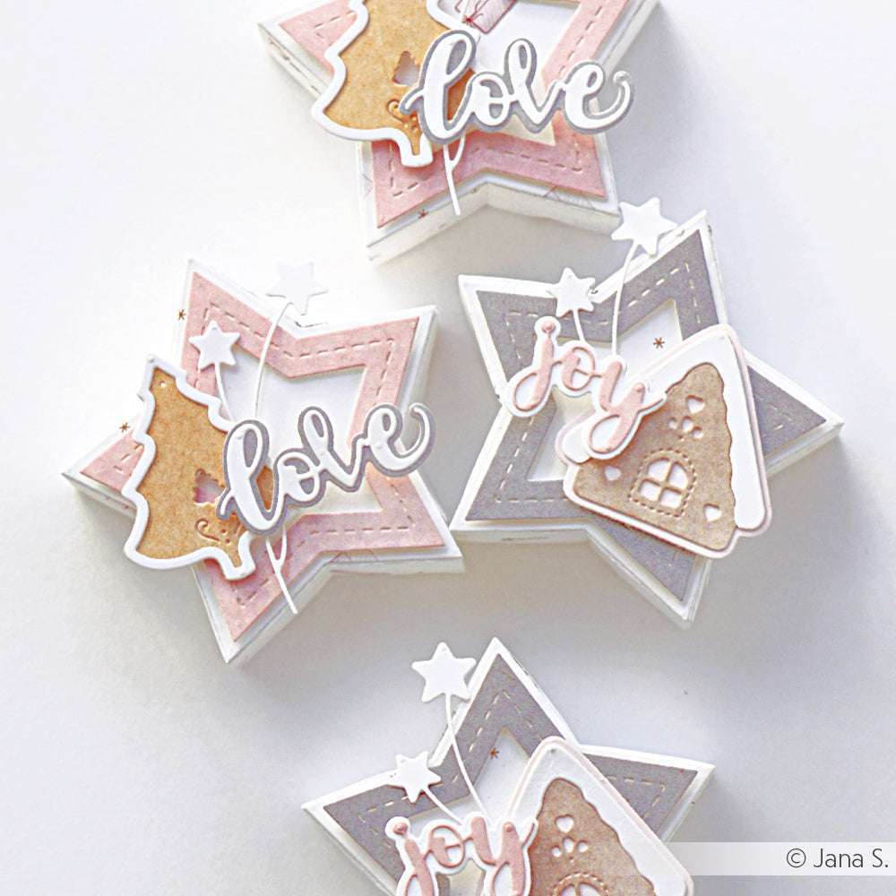 Drei sternförmige Karten von Alexandra Renke, die mit der Motivstanze Weihnachtsbaum gestaltet wurden, sind mit dem Text "Liebe" oder "Freude" und festlichen Plätzchen in Rosa-, Gold- und Grautönen versehen.