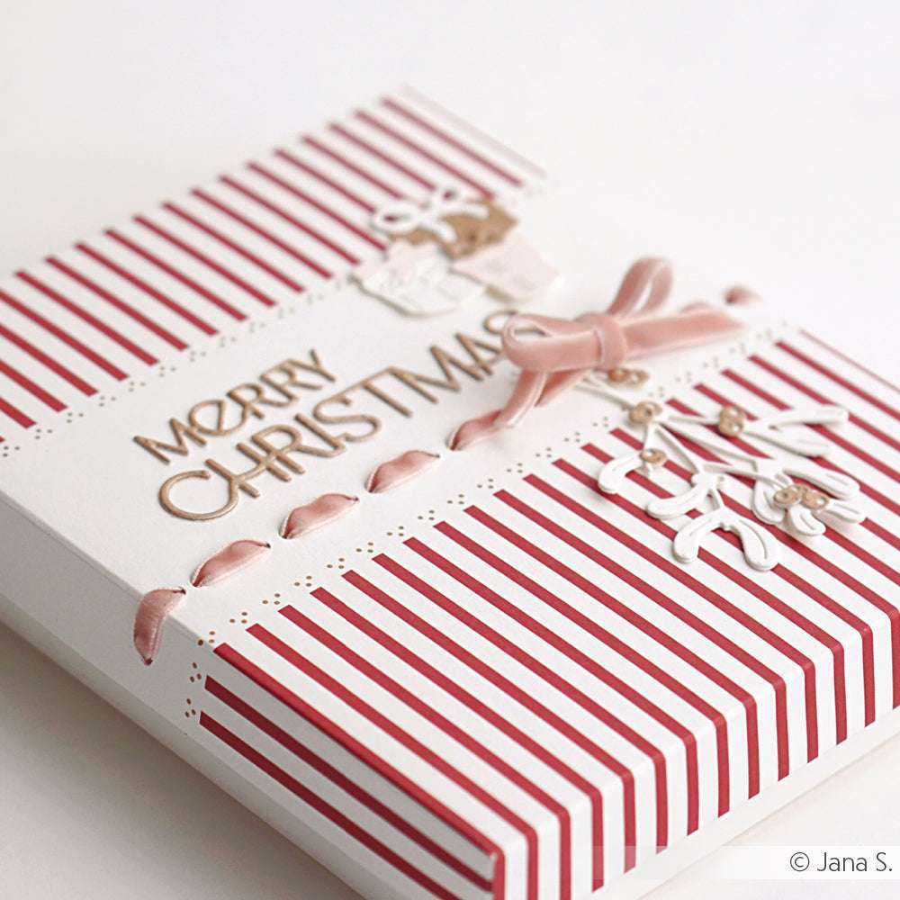 Eine rot-weiß gestreifte Weihnachtskarte mit "Frohe Weihnachten" und einer rosa Schleife auf der Vorderseite, die mit Produkten von Alexandra Renke gestaltet wurde und einen festlichen Touch hat.