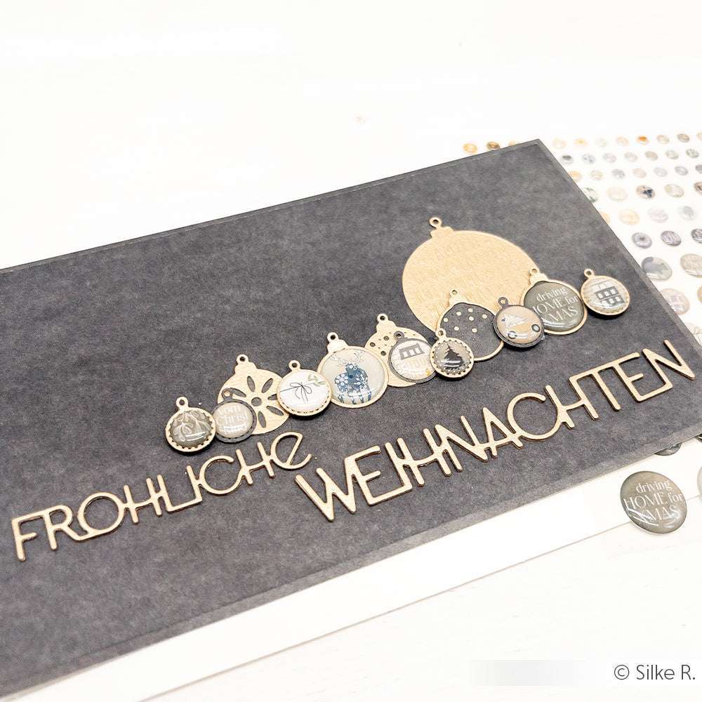 Handgemachte Weihnachtskarte von Alexandra Renke mit der Stanze "Fröhliche Weihnachten", hängenden Kugeln auf dunklem Hintergrund und hochwertigem Designpapier für einen festlichen Look.
