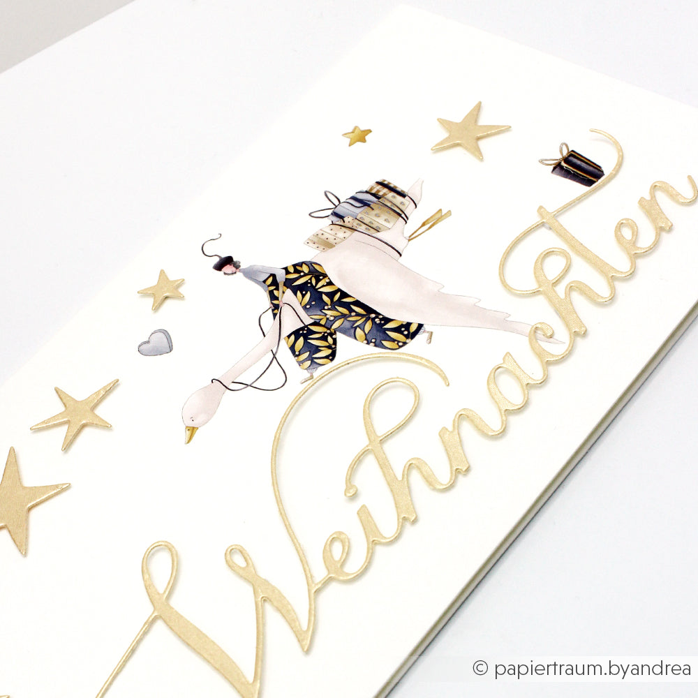 Grußkarte von Alexandra Renke mit goldenen Sternen und einer illustrierten Frau, die auf einer Gans mit Geschenken reitet, hergestellt auf Designpapieren und veredelt mit der Motivstanze Kalligrafisch Weihnachten für einen eleganten festlichen Touch.