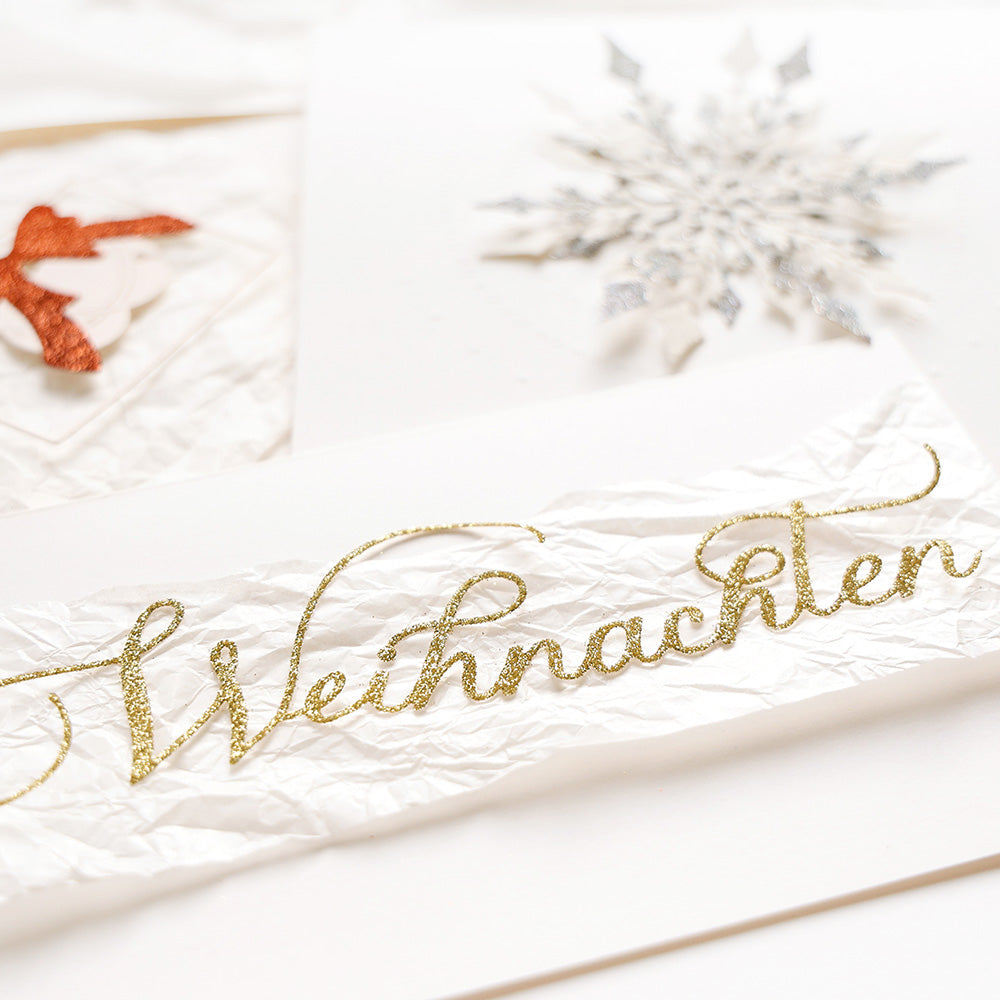 Weiße Karte von Alexandra Renke mit "Weihnachten" in goldener Kalligrafieschrift, festlicher Ornamenthintergrund - eine ideale Ergänzung für Ihre Weihnachtsbasteleien mit DieCut Systemen.