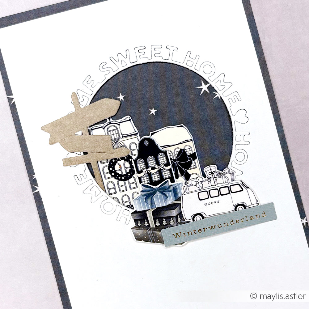 Das Designpapier von Alexandra Renke zeigt eine winterliche Collage mit Häusern, Geschenken, Lieferwagen, dem Text "Winterwunderland", Motivstanze-Akzenten und einem charmanten "Home sweet home"-Typo-Kreis auf strahlendem Weiß.