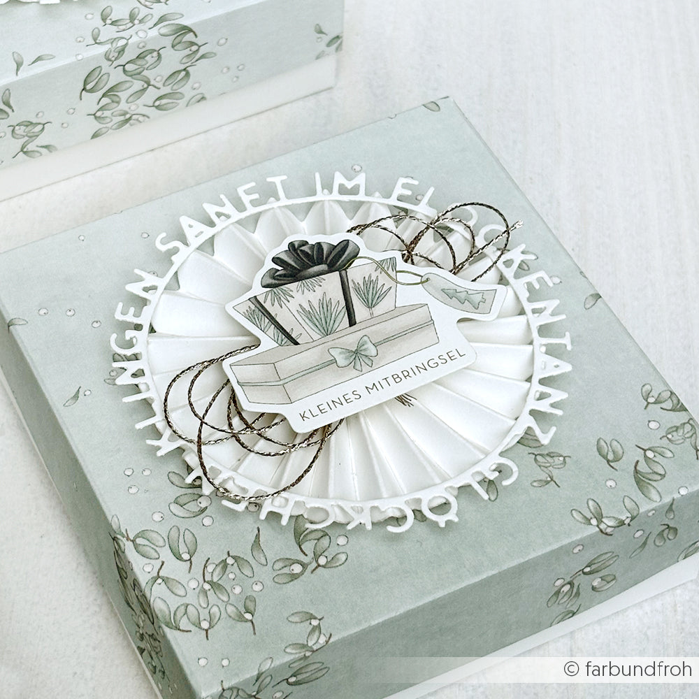 Geschenkbox mit floralem Muster, verziert mit einer Rosette und einem Geschenkmotiv, mit deutschem Text auf dem Deckel - gefertigt mit der Motivstanze Glöckchen klingen von Alexandra Renke für ein besonders charmantes Detail.