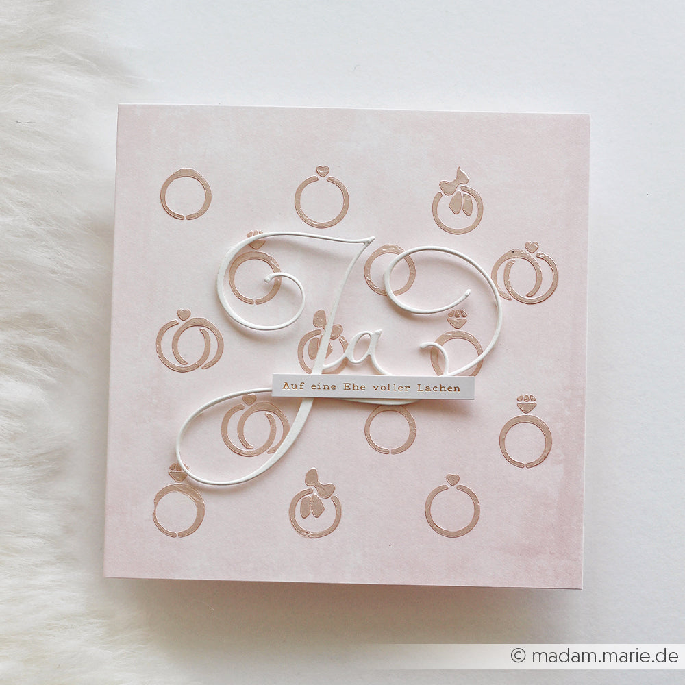 Quadratische Hochzeitskarte von Alexandra Renke mit Ringen, einer kursiven "Kalligrafisch Ja"-Stanzung und "Auf eine Ehe voller Lachen" auf Beige - fachmännisch mit DieCut Systemen hergestellt für einen eleganten Look.