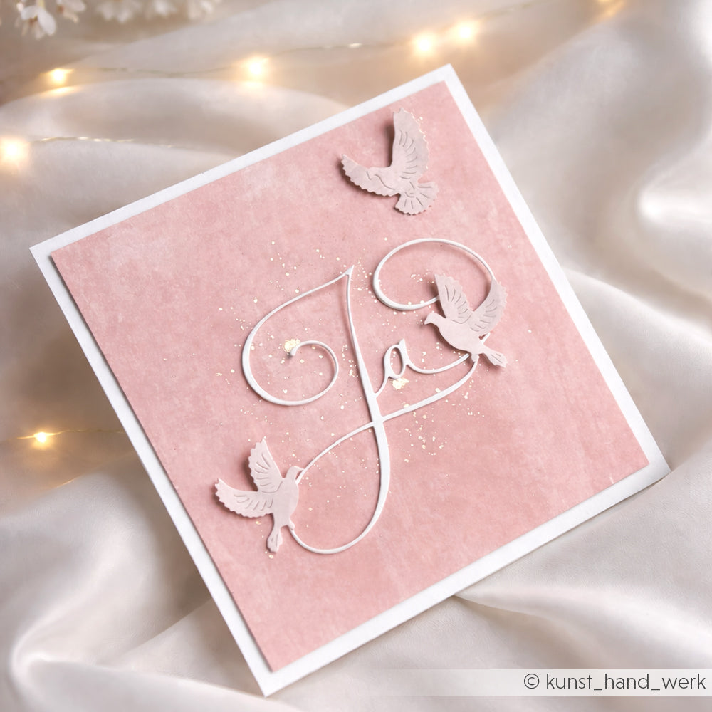 Elegante rosa Hochzeitskarte von Alexandra Renke mit Kalligrafisch Ja-Schriftzug, drei weißen Tauben, sanften Lichtern und auf hochwertigem Designpapier.