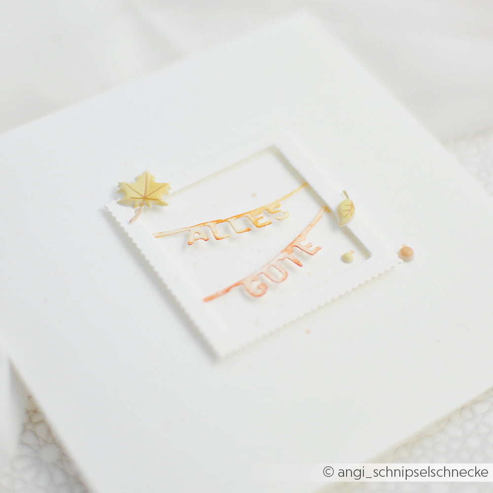 Weiße Karte mit einem quadratischen 3D-Rahmen, verziert mit winzigen Bändern, die mit der Motivstanze „Wort-Girlanden“ gestaltet wurden und die Aufschrift „ALLES GUTE“ tragen, akzentuiert durch kleine Blatt- und Herzverzierungen – perfekt ergänzt durch filigrane Stanzteile von DieCut Systeme für ein edles Finish.