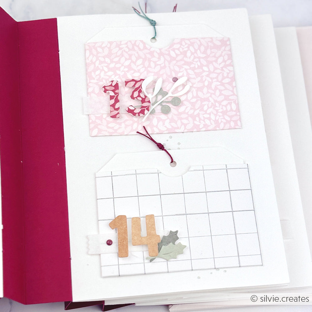 Zwei handgefertigte Scrapbook-Anhänger mit den Zahlen 13 und 14, ausgeschnitten aus Designpapier.