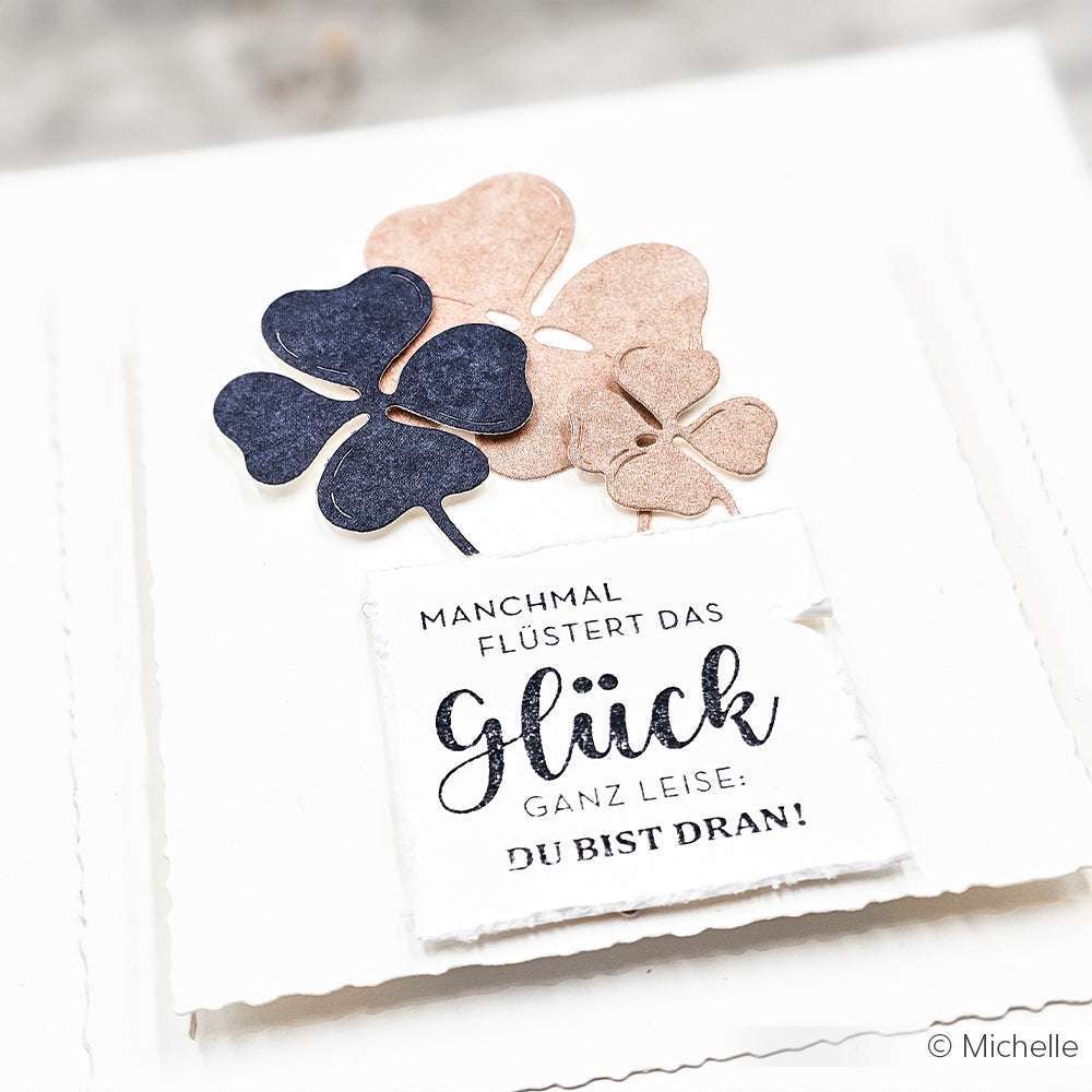 Papierkleeblätter und eine Karte mit dem deutschen Spruch "Manchmal flüstert das Glück ganz leise: Du bist dran!" - verziert mit charmanten Details aus Alexandra Renke Stempel Holz und leuchtenden Stempelkissen.