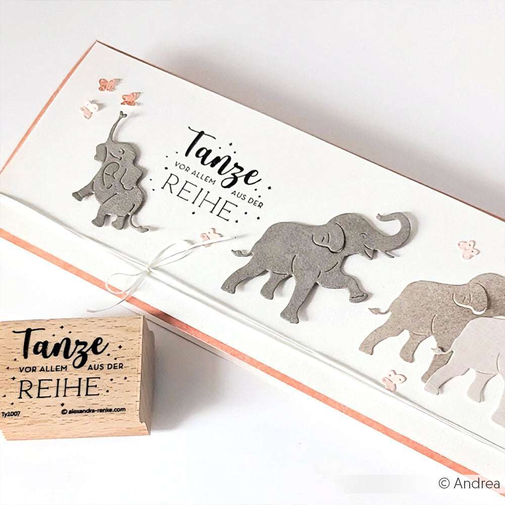 Handgemachte Karte von Alexandra Renke mit grauen Elefanten, rosa Schmetterlingen und deutschem Text neben einem passenden Holzstempel - ideal für einzigartige Papierprojekte.