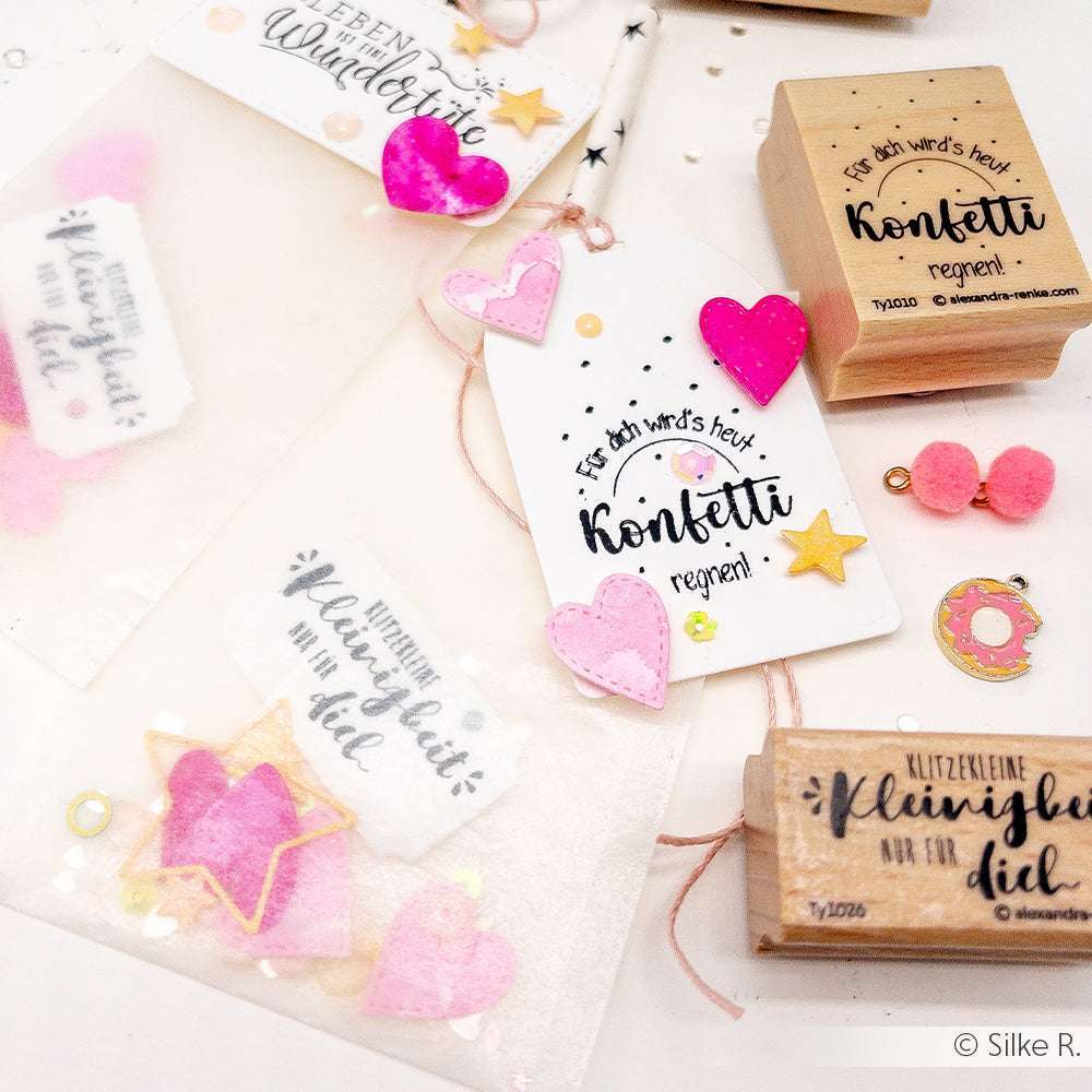 Handgefertigte Geschenkanhänger von Alexandra Renke mit rosa Herzen, Sternen und Stempelmotiven auf weißem Hintergrund mit Konfetti-Akzenten.