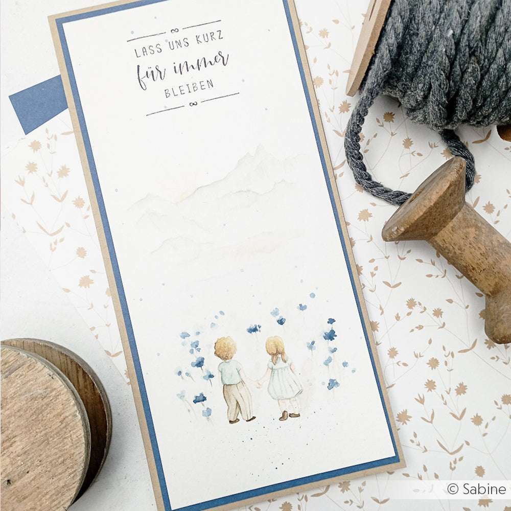 Handgefertigte Karte von Alexandra Renke mit zwei Kindern in einem Blumenfeld und der Aufschrift "Lass uns kurz für immer bleiben." Entworfen mit sorgfältig ausgewählten Stempelkissen und hochwertigen Holzstempeln für einen einzigartigen Look.