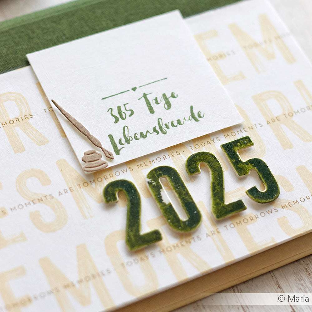 Eine Karte von Alexandra Renke mit "365 Tage Lebensfreude" und grünen 2025er Zahlen auf gemustertem Hintergrund, mit einem charmanten Holzstempel/Stempelgummi-Design.