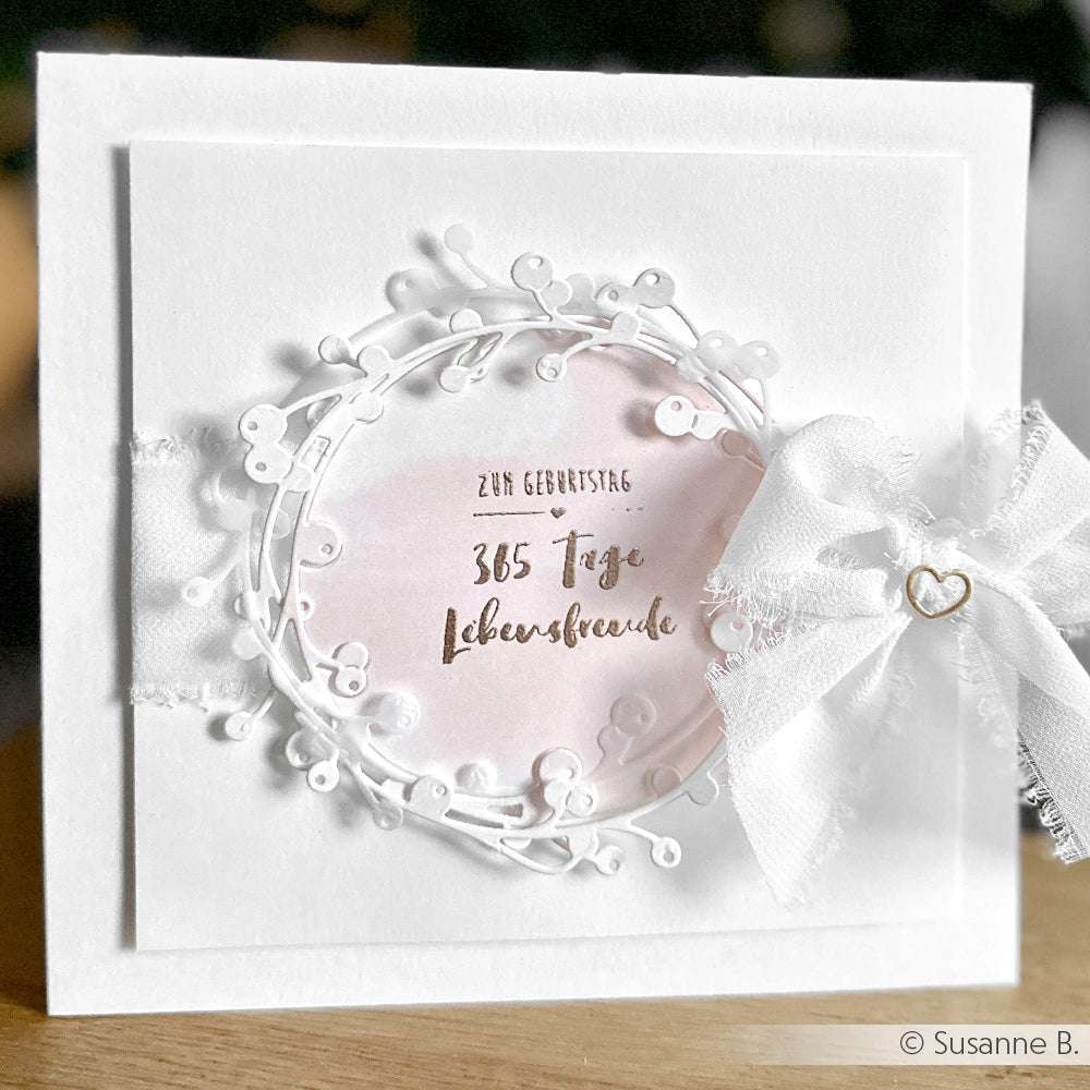 Die weiße Geburtstagskarte von Alexandra Renke zeigt einen Spitzenkranz, eine rosa Mitte und eine weiße Schleife mit Herzanhänger - perfekt, um 365 Tage Lebensfreude an einem besonderen Tag zu teilen.