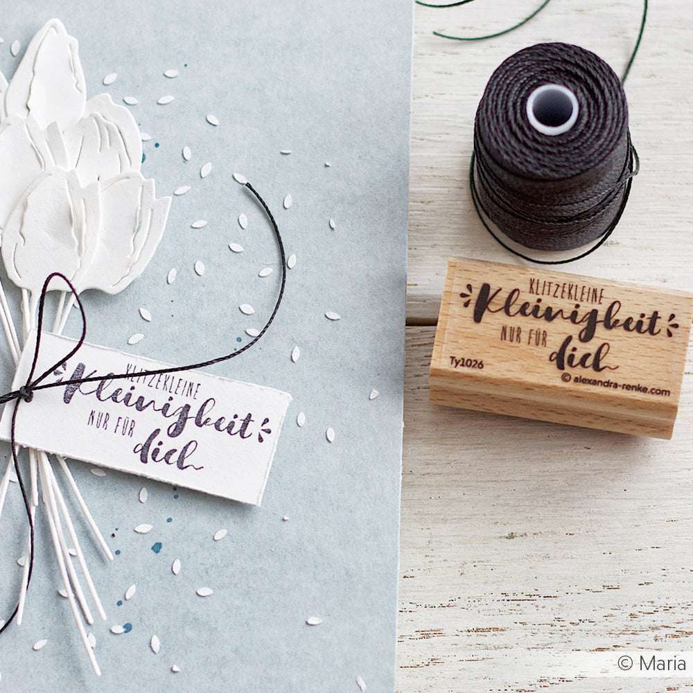 Handgemachte Karte von Alexandra Renke mit weißen Papierblumen, schwarzer Schnur und einem gestempelten Anhänger auf hellblauem Grund - ideal für Papierprojekte oder Ihre Lieblings-Stempelgummi-Designs.