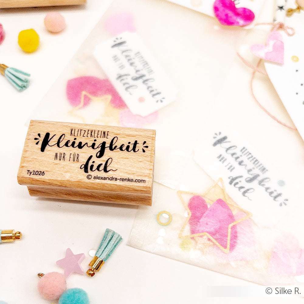 Ein Alexandra Renke Holzstempel mit deutschem Text, bunten Quasten, Bommeln und verzierten Geschenktüten - ideal für Ihre Papierprojekte.