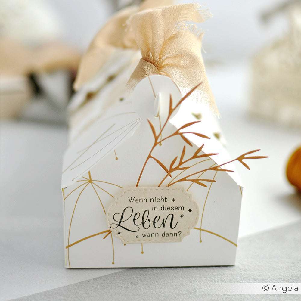 Weißer Geschenkkarton von Alexandra Renke mit goldenen Akzenten, beigem Band und deutschem Textetikett - ideal zum Präsentieren von Papierprojekten oder zum Ausstellen Ihrer liebsten Stempelgummi oder Holzstempel-Kreationen.