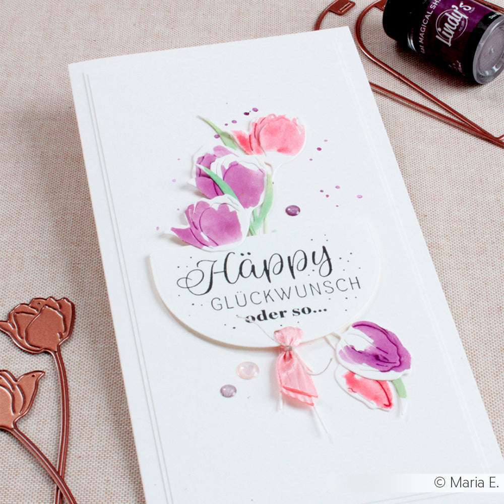 Eine handgefertigte Karte von Alexandra Renke mit gemalten rosa und lila Tulpen, deutschem Text "Happy Glückwunsch oder so...", und einem charmanten Holzstempel-Akzent für eine besondere Note.