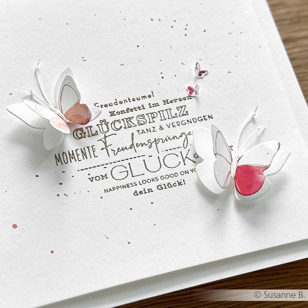 Handgemachte Karte von Alexandra Renke mit deutschen Worten und zwei 3D-Papierschmetterlingen, akzentuiert mit rosa und brauner Aquarellfarbe - ideal für Papierprojekte oder als Inspiration für Stempelgummi-Designs.