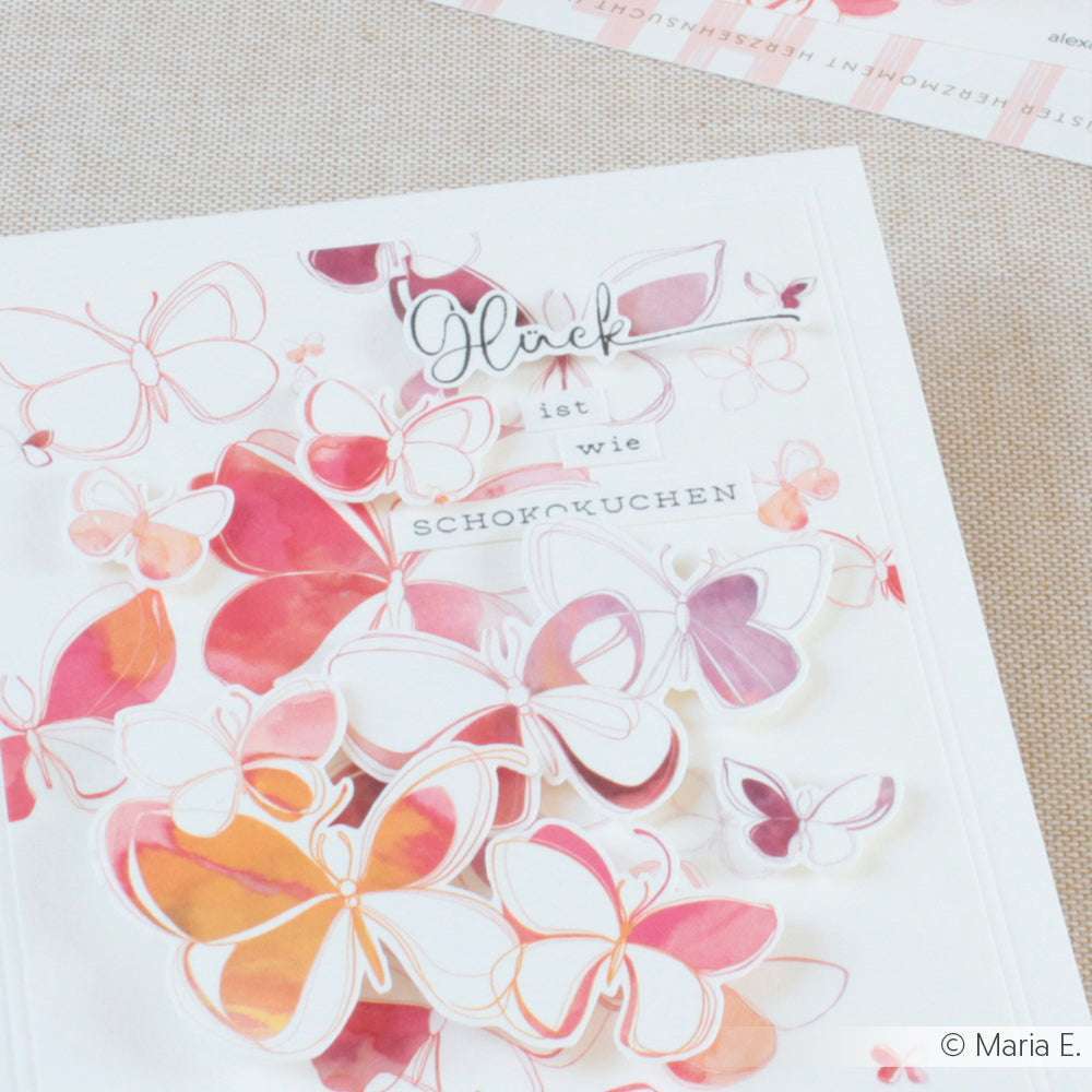 Eine bezaubernde, handgefertigte Karte von Alexandra Renke, verziert mit rosa, orangefarbenen und lila Schmetterlingen und deutschem Text in der Mitte, mit Details, die mit Holzstempeln oder Stempelgummi hergestellt wurden.