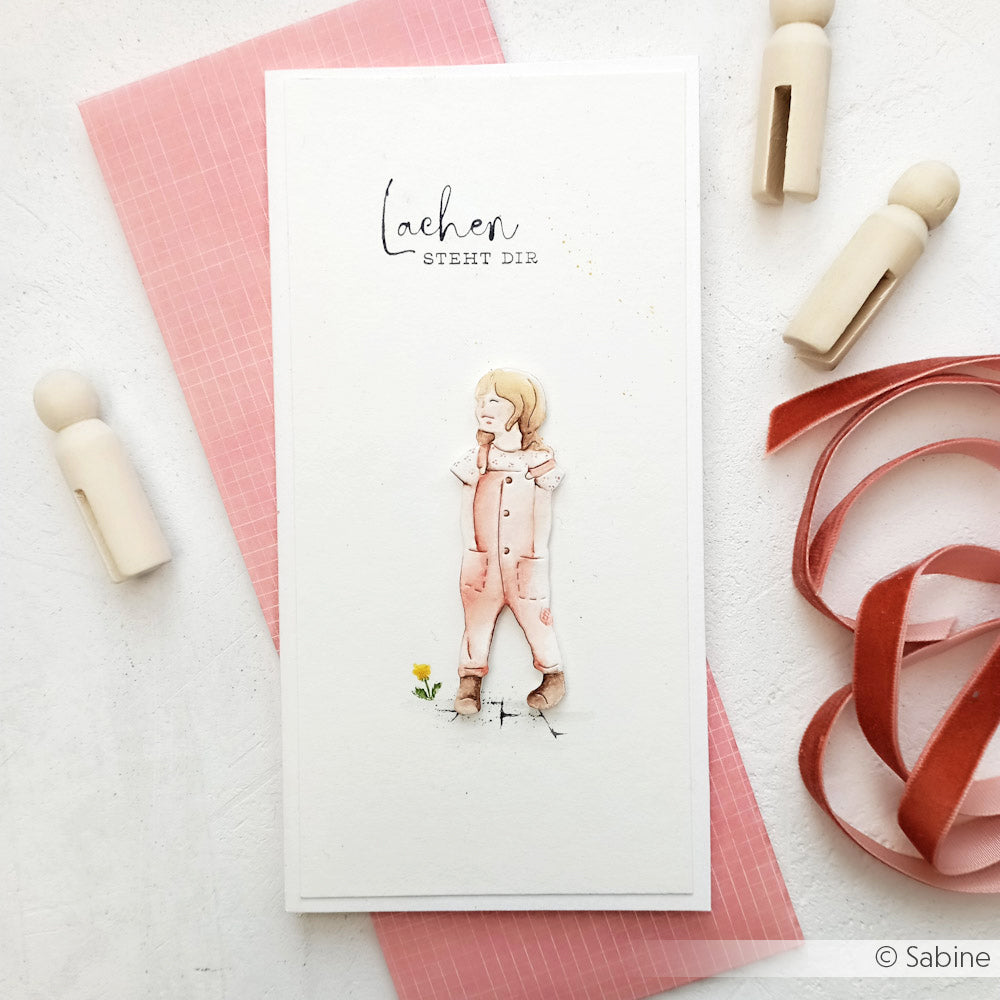 Handgefertigte Karte von Alexandra Renke mit einem aquarellierten Kind in rosa Latzhose, Text oben, fertig mit Band und Holzklammern - ideal für Papierprojekte oder in Kombination mit Ihrem Lieblingsholzstempel.