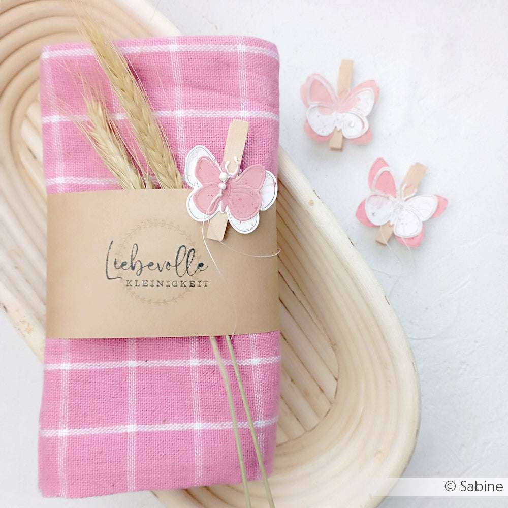 Rosa karierte Serviette mit Weizenstängeln, eingewickelt in Kraftpapier und verziert mit rosa Schmetterlingsklammern von Alexandra Renke - eine ideale Inspiration für kreative Papierprojekte oder Holzstempel-Designs.