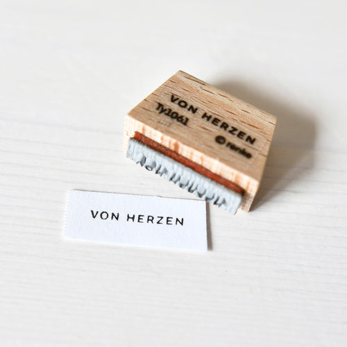 Eine Briefmarke von Alexandra Renke mit einem Mini-Typo-Motiv und dem Bild eines Holzstempels - perfekt für Sammler.