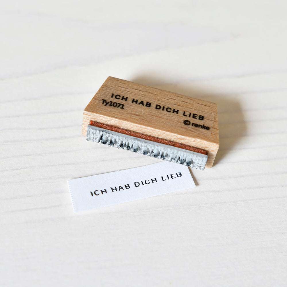 Der Holzstempel von Alexandra Renke und das passende gestempelte Papier, beide mit "ICH HAB DICH LIEB", sind ideal für Papierprojekte oder als charmanter Mini-Typo-Akzent für Ihre Bastelarbeiten.