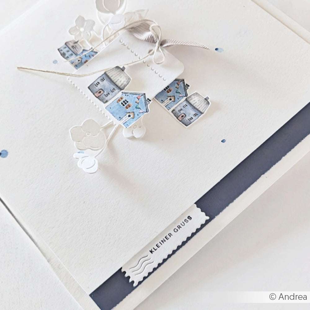 Handgemachte Grußkarte von Alexandra Renke mit blauen Hausausschnitten, weißen Blumenakzenten und "KLEINER GRUSS", gestempelt mit einem Mini Typo Holzstempel.