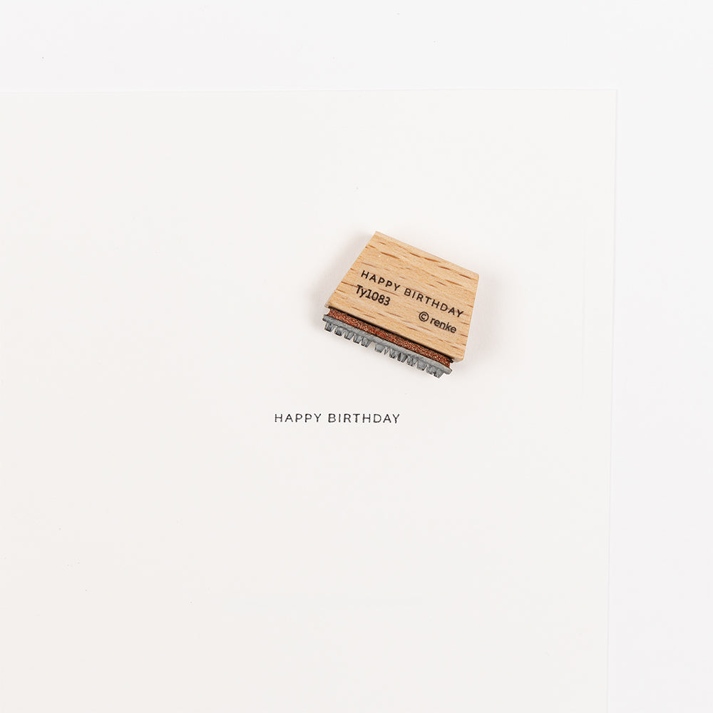 Ein Holzstempel mit Holzgriff, auf dem unten auf weißem Hintergrund „HAPPY BIRTHDAY“ aufgedruckt ist – ideal für die Verwendung mit Ihrem Lieblings-Stempelkissen.