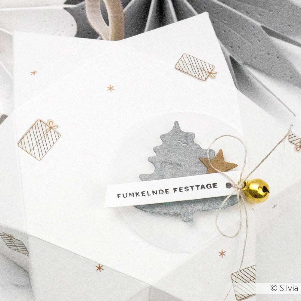 Weiße Geschenkschachtel mit weihnachtlicher Dekoration, einer kleinen Glocke und einem Anhänger mit der Aufschrift "Funkelnde Festtage" von Alexandra Renke - ideal für Papierprojekte oder zum Personalisieren mit Stempelgummi oder Holzstempel.