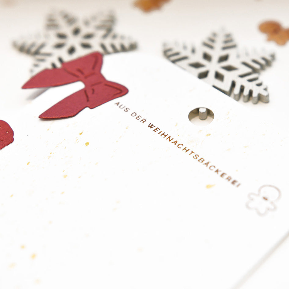 Nahaufnahme einer festlichen Karte von Alexandra Renke mit roten Ausschneideformen, Schneeflockenverzierungen, deutschem Text und gestempelten Details - perfekt für jede Weihnachtsbäckerei.