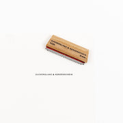Holzstempel mit der Aufschrift ZUCKERGLANZ & KERZENSCHEIN neben dem Stempelabdruck.