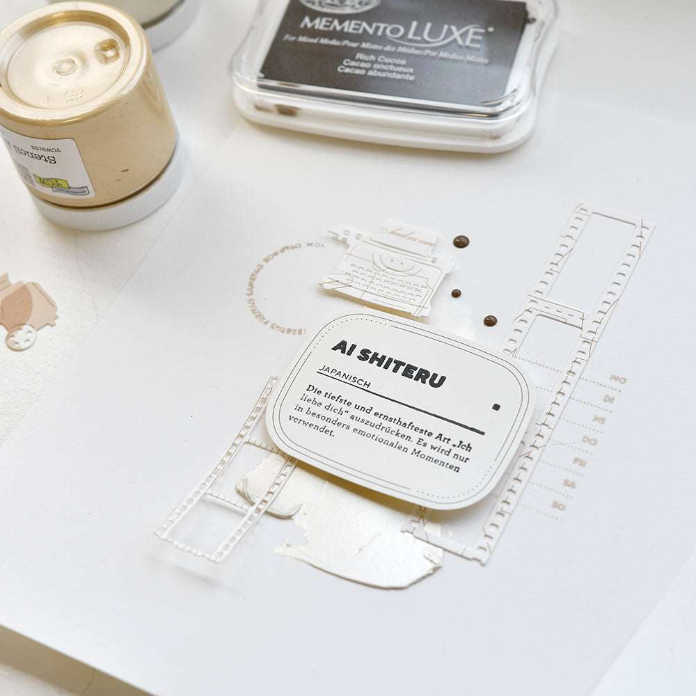 Eine Scrapbook-Seite mit Filmstreifen, einer "AISHITERU"-Karte und Stempelkissen auf weißem Untergrund - die perfekte Inspiration für Papierprojekte mit Alexandra Renke Stempelgummi oder Holzstempel.