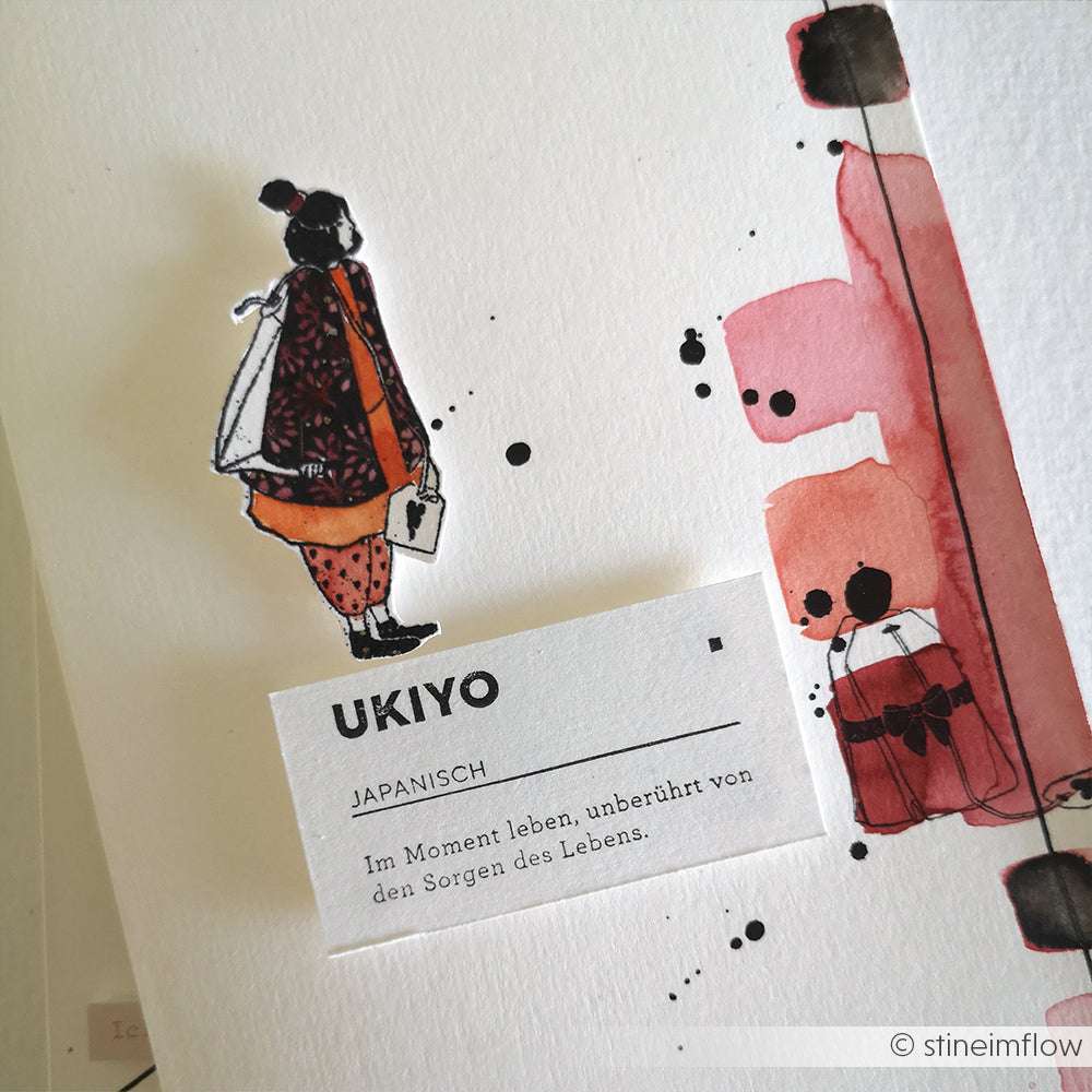 Eine ausgeschnittene Figur und abstrakte Aquarelle, die mit dem Holzstempel von Alexandra Renke gemalt wurden, stehen neben einer Karte, die das japanische Wort Ukiyo erklärt.