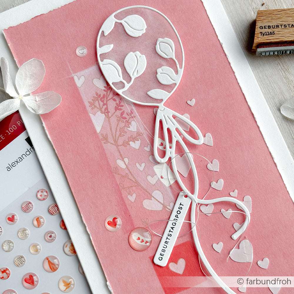 Eine handgefertigte Karte von Alexandra Renke mit weißem Luftballon und Herzmotiv auf rosafarbenem Papier, mit einem "Geburtstagspost"-Etikett - ideal für Papierprojekte und gestempelt mit einem charmanten Holzstempel.