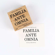 Ein Holzstempel von Alexandra Renke und Papier zeigen beide das Motiv "FAMILIA ANTE OMNIA - FAMILY ABOVE ALL".