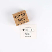 Ein Alexandra Renke Holzstempel und eine gestempelte Karte mit "TOI ET MOI, YOU AND ME" in Deutsch, Französisch und Englisch - ideal für Papierprojekte mit hochwertigem Stempelgummi.