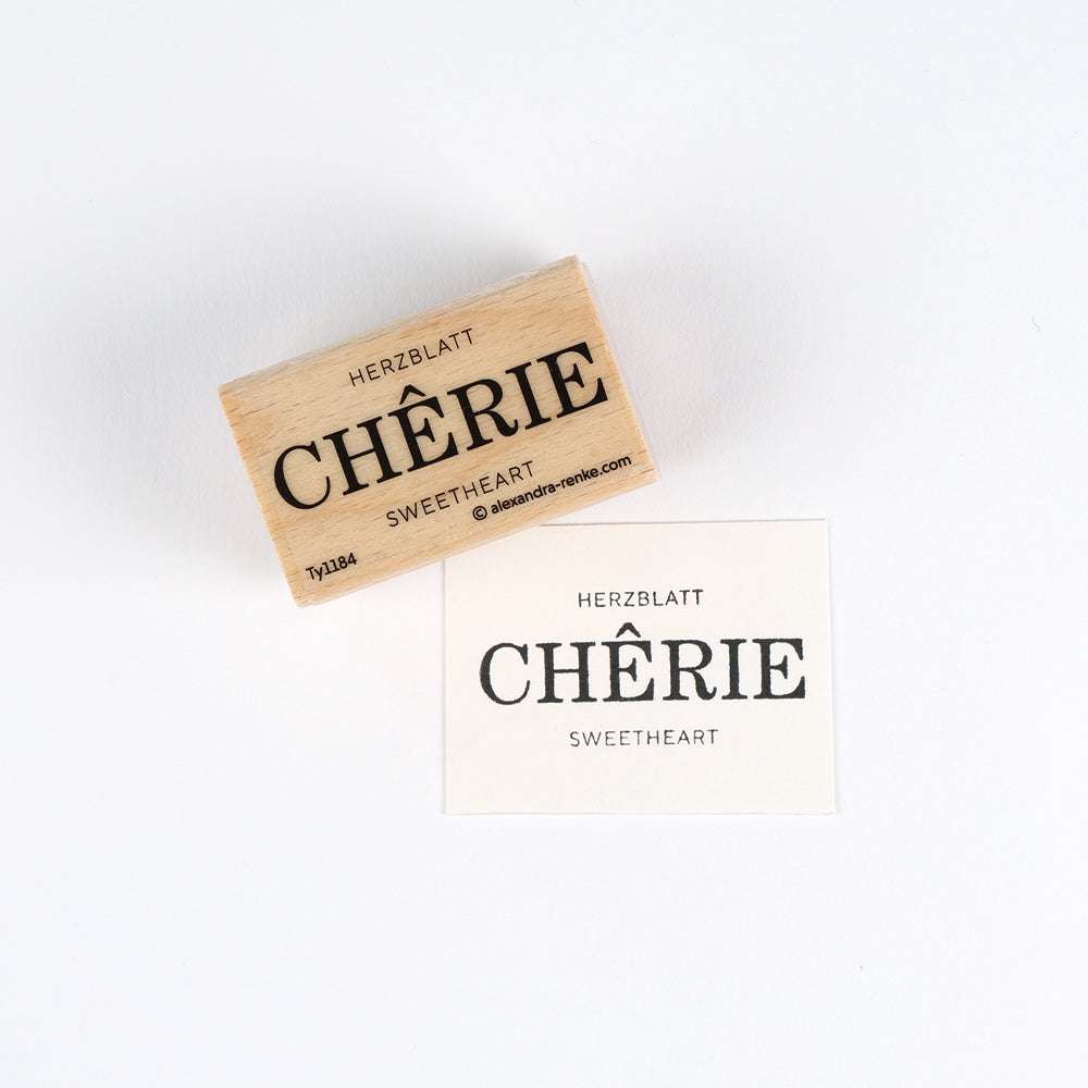Ein Holzstempel von Alexandra Renke und ein gestempeltes Papier zeigen HERZBLATT CHÉRIE SWEETHEART in Schwarz auf Weiß, wobei hochwertige Materialien für gestochen scharfe, bleibende Eindrücke verwendet wurden.